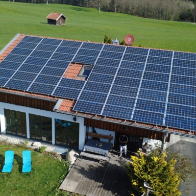 Das Bild zeigt das Ferienhaus mit Solaranlage auf dem Dach eingebetet in grüne Wiesen